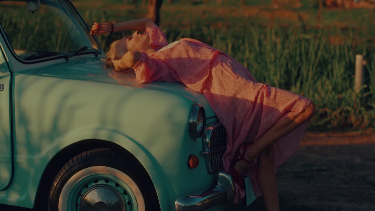 Woman in Pink Dress on a Vintage Car at Sunset