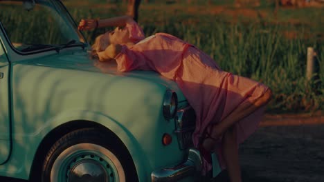 woman in pink dress on a vintage car at sunset