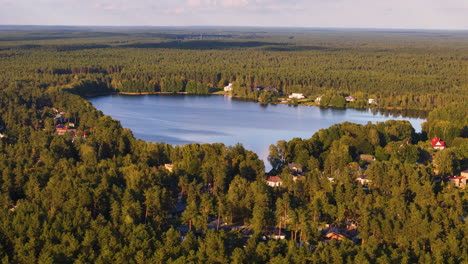 langstini is a sweet town in latvia surrounded by verdant forests and nature attractions around this beautiful lake. aerial rotation above lakeside homes.
