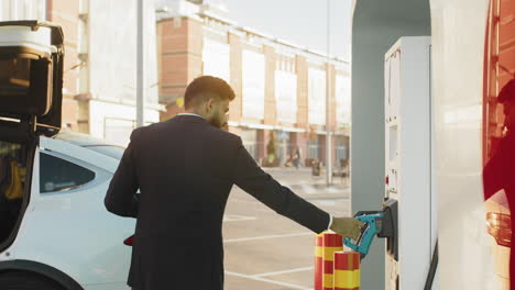 hombre cargando un vehículo eléctrico en una estación de carga