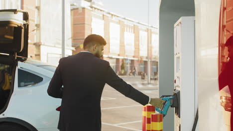 man charging electric vehicle at charging station