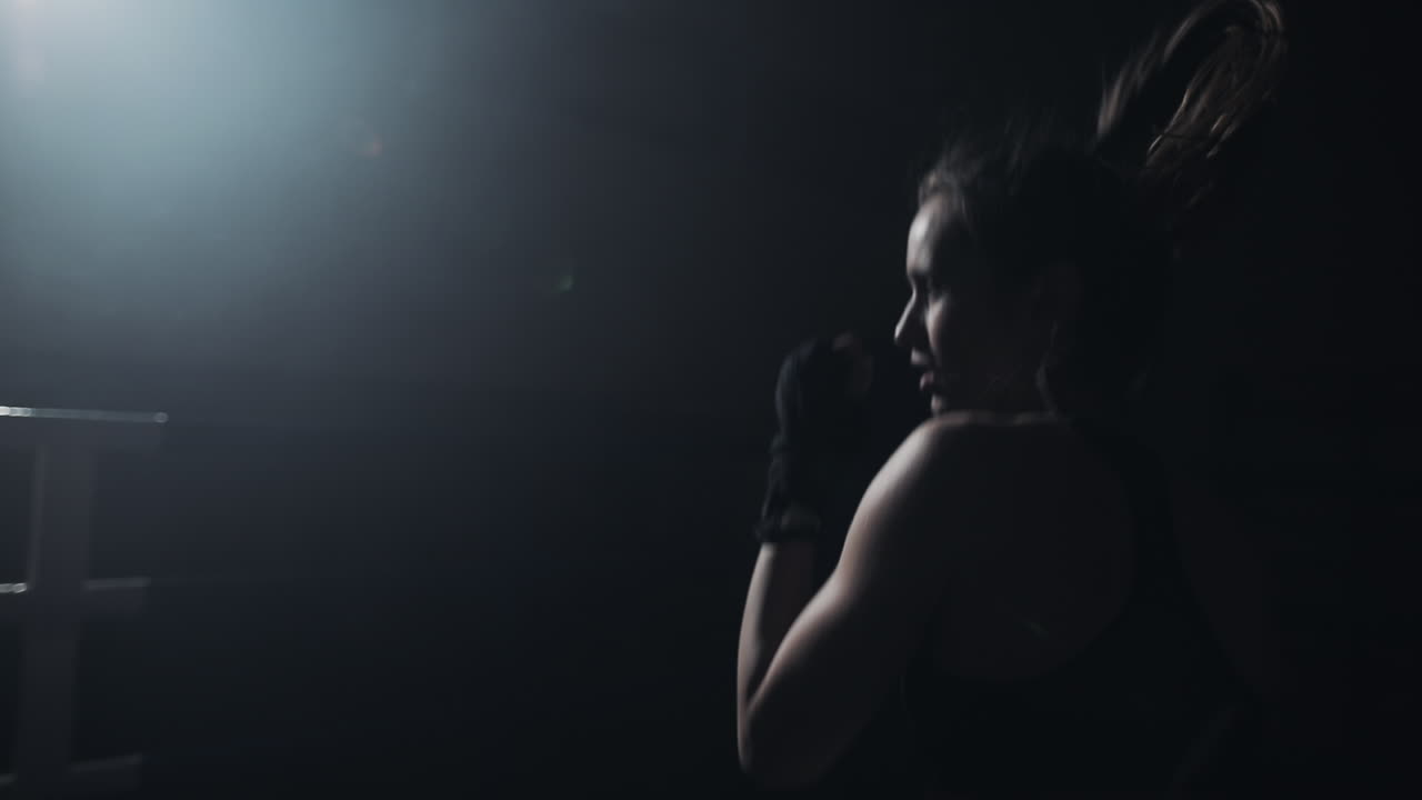 Female Boxer Training in a Dark Ring