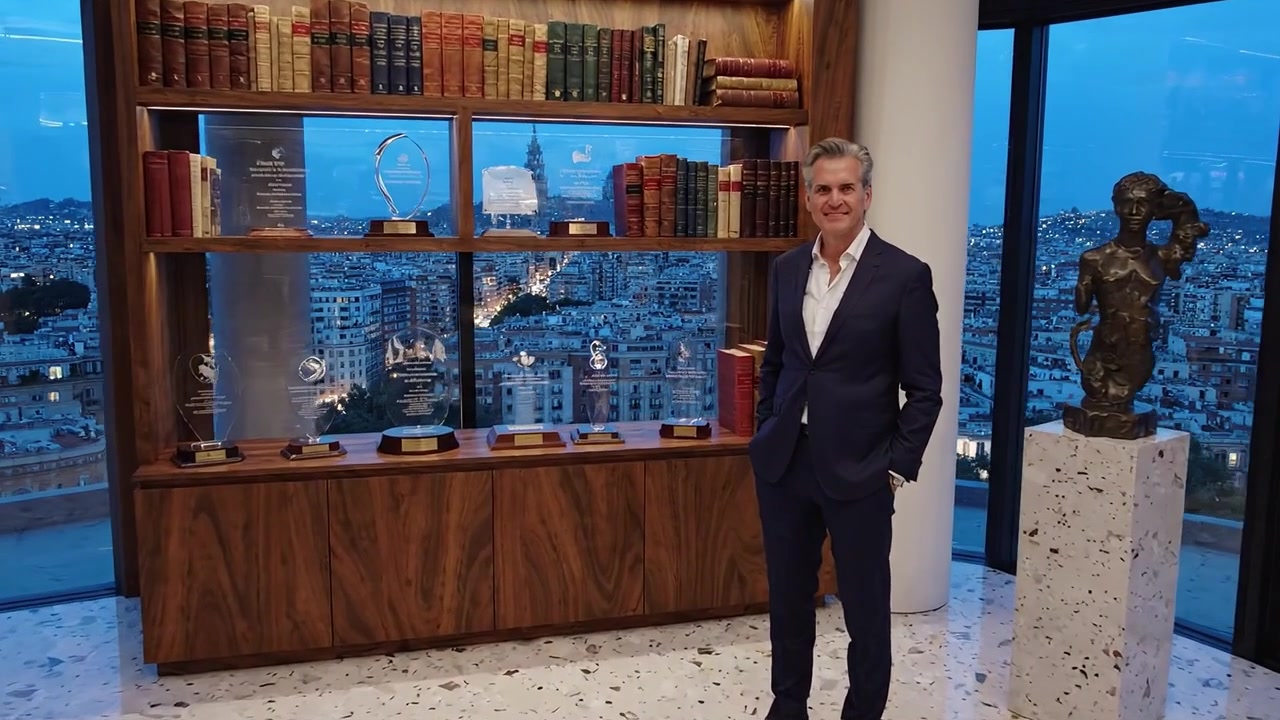 Interno moderno ed elegante con busti e librerie, affacciato sulla città, che mostra un uomo in abito con premi e opere d'arte in un ambiente lussuoso.