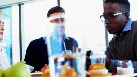 Executives-discussing-while-having-breakfast-together-in-the-cafeteria