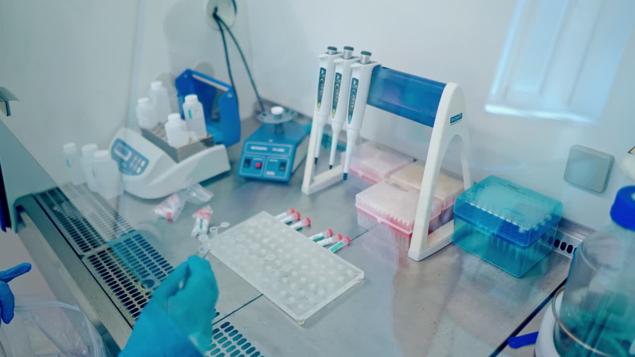 Výzkumník pracuje na klinice. Laborant umisťuje vzorky krve do stojanu.