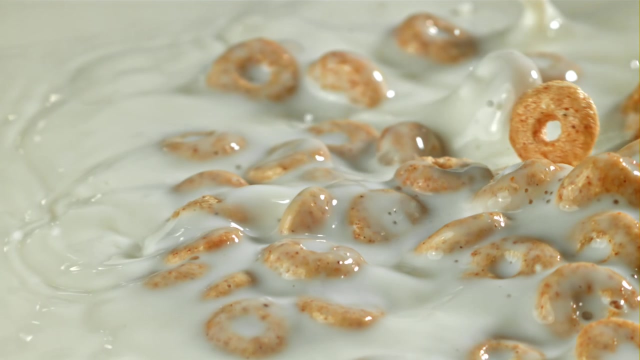 Anelli di cereali che cadono nel latte fresco al rallentatore