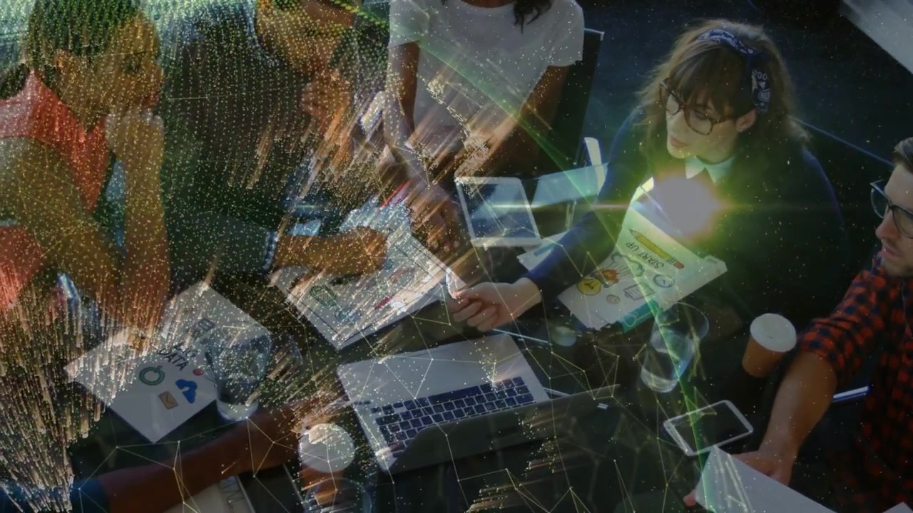 Team around table pointing laptop, reaching tablet and comparing designs, network overlay growing