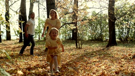 happy girl running ahead of their parents in the autumn park