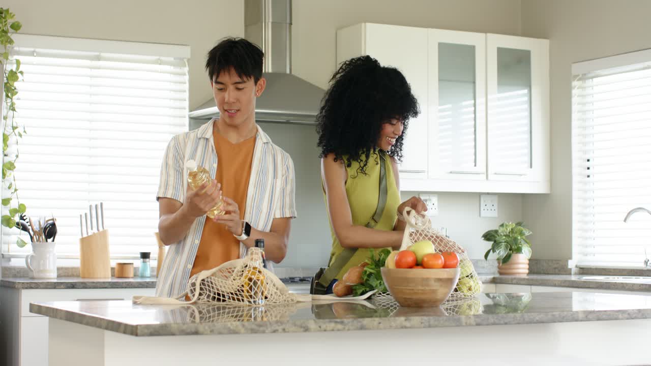 Couple unpacking reusable bags in kitchen after grocery shopping, inspecting produce for dinner