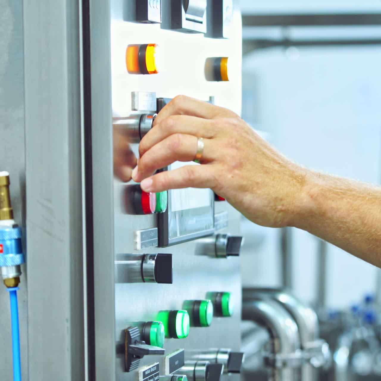Male worker in special uniform launch robotic machine in the factory. Contemporary equipment of a dairy factory at work. Manufacturing background.