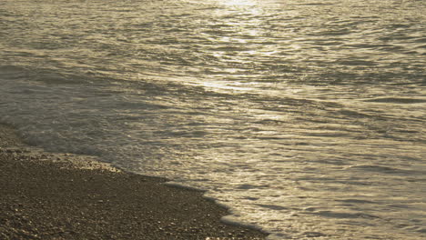 Olas-Iridiscentes-Del-Mar-Al-Atardecer-Golpeando-La-Costa-Con-Luz-Dorada-En-La-Playa