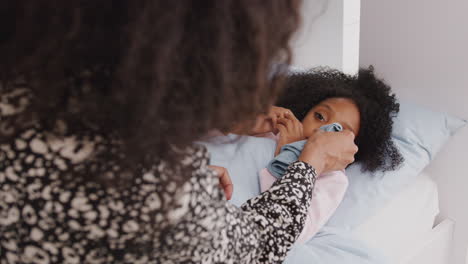 madre cuidando a su hija enferma enferma en la cama con frío entregándole un pañuelo