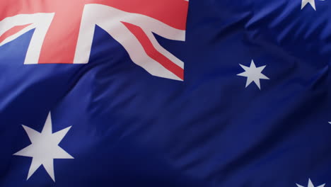 white rugby ball rolling over waving flag of australia with copy space, in slow motion