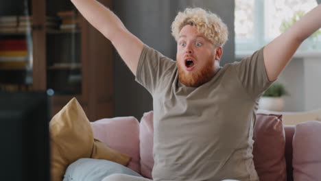 overweight man watching sport match on tv and celebrating goal