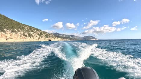wake of a motorboat at sea sailing off the coast of a sunny island - cala gonone sardinia
