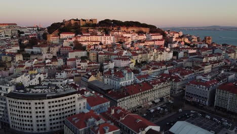 aerial view of lisbon city with old buildings and castle during golden hour