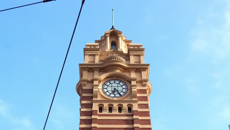 Iconic-landmark-of-Melbourne-city,-the-majestic-clock-tower-of-Flinders-street-railway-station-against-beautiful-blue-sky-background,-close-up-shot