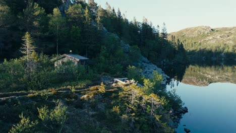 Mjøvatnet,-Indre-Fosen,-Trøndelag,-Norway---A-Cozy-Wooden-Cabin-Situated-by-the-Lake---Orbit-Drone-Shot