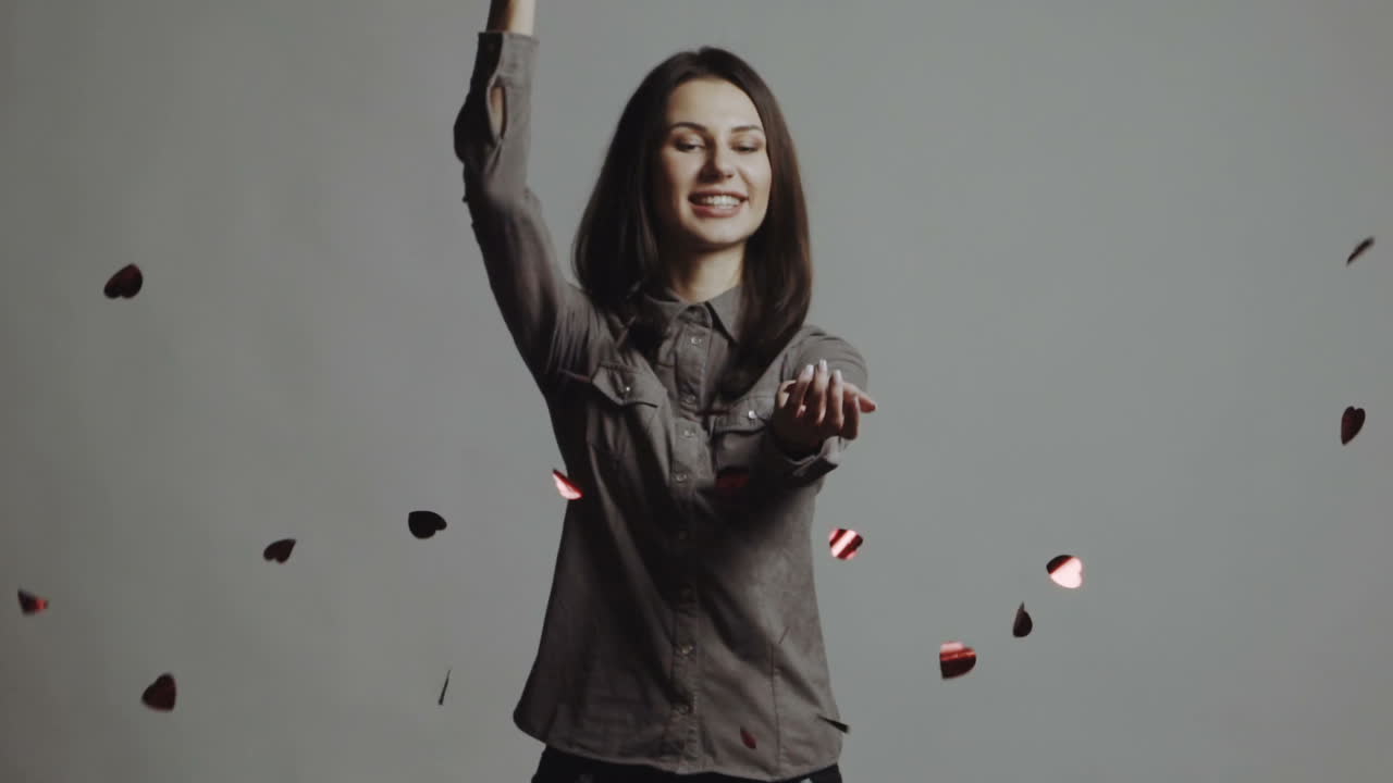 Giovane donna che afferra cuori di carta su sfondo bianco. Movimento lento.