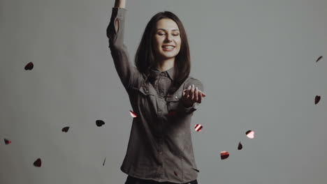 young woman catching paper hearts over white. slow motion