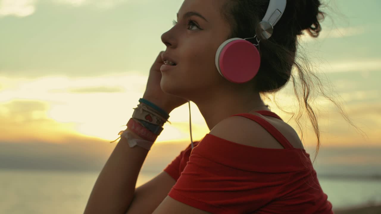 una adolescente con auriculares escuchando música en la playa. filmada a cámara lenta