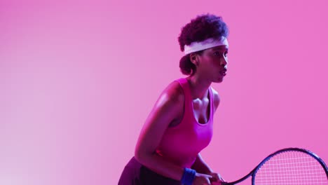 video of focused african american female tennis player hitting ball on neon pink lightning