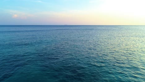 Impresionante-Cielo-Degradado-Amarillo-Atardecer-Sobre-Ondas-Onduladas-De-Textura-De-Agua-Del-Océano,-Plataforma-Rodante-De-Drones