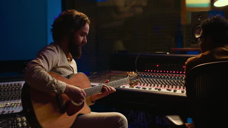 musician and sound engineer recording guitar tunes in control room