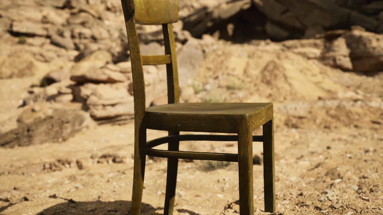 Unique wooden chair placed on sandy desert terrain under bright sunlight