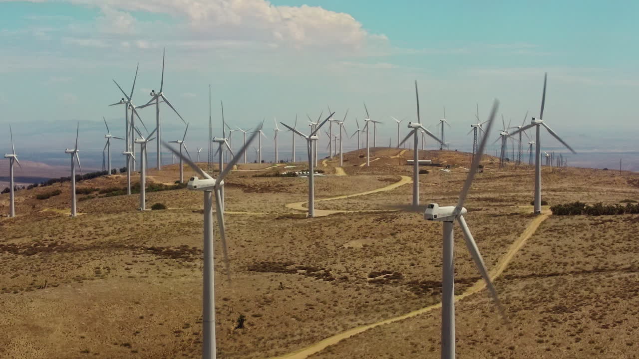 A static shot of windmills operating at the top of a hill