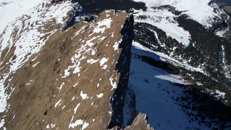 Aerial-View-of-Seceda-Mountain-Ridgeline,-Sharp-Dolomite-Rocks-and-Snow-on-Sunny-Spring-Day,-Italy