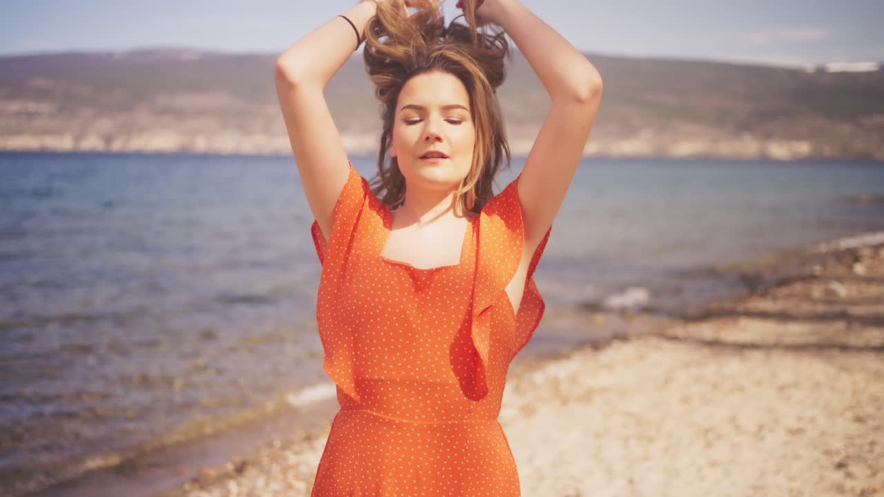 Filrty girl in red dress on a windy beach