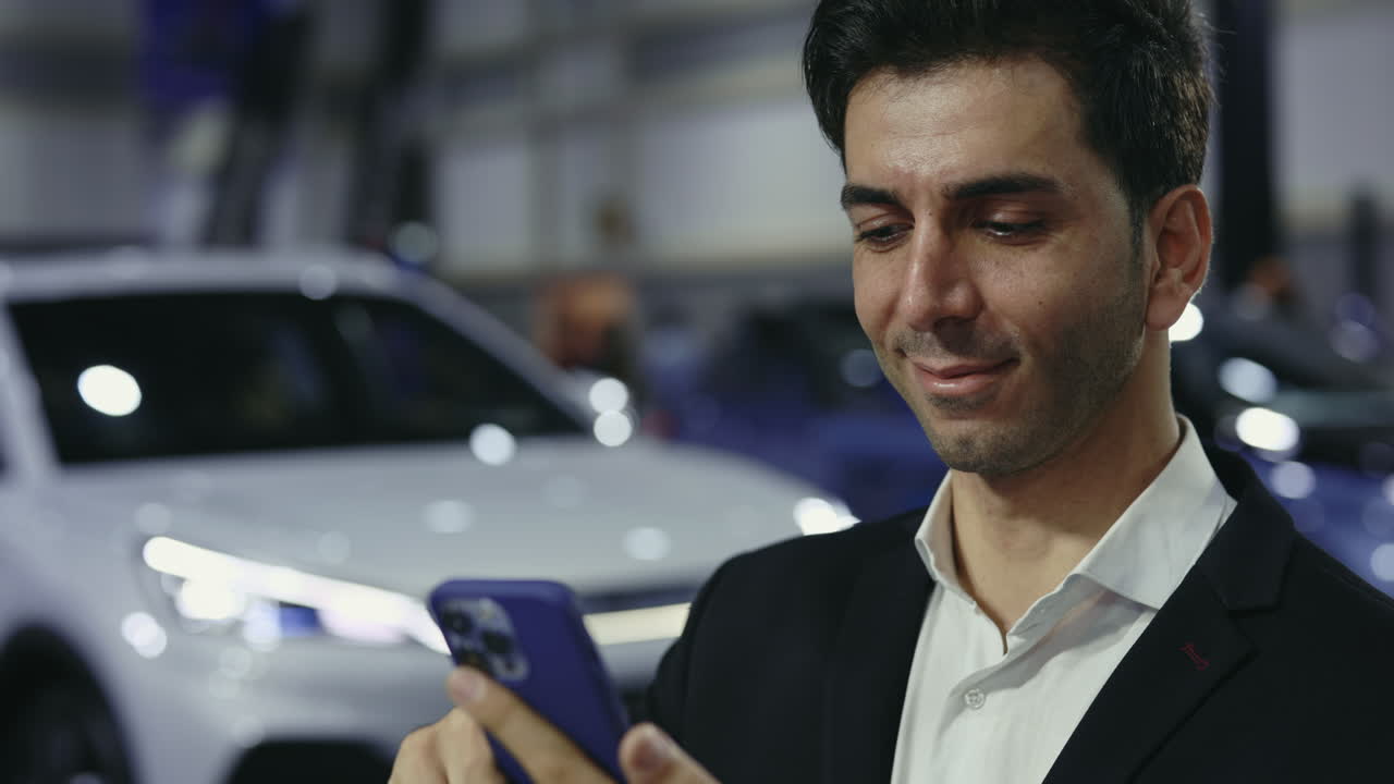 Businessman at a car show looking at his phone