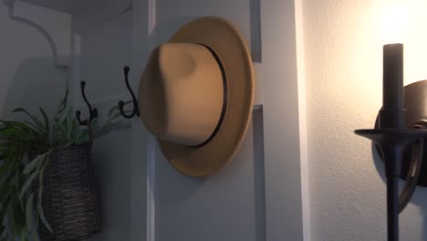 fedora hanging on the back of a door in a home