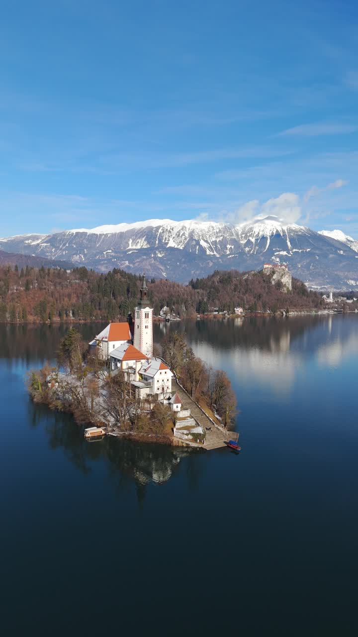 La chiesa dell'isola di Bled si trova sul lago di Bled con il castello sullo sfondo, vista aerea verticale