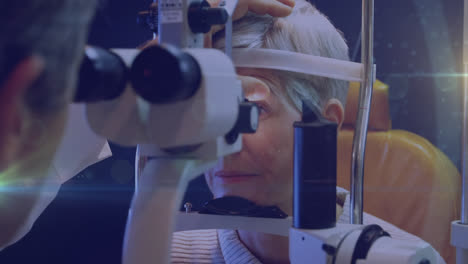 un punto brillante de luz contra una mujer mayor que se examina los ojos.
