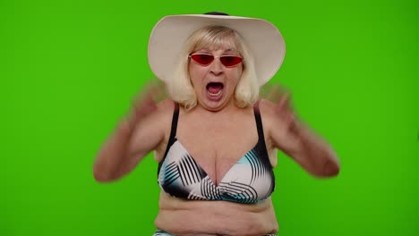 senior woman tourist raising hand in victorious gesture, dancing shouting yes, celebrating success