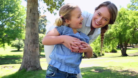 madre feliz sosteniendo a su niña en el parque y girando