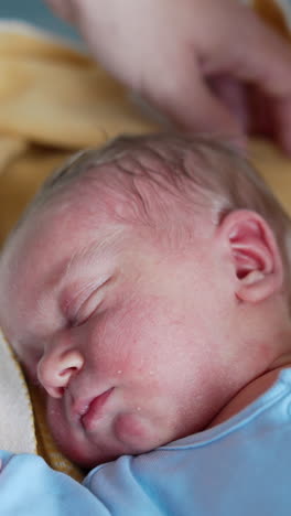 hands of parents in the crib around the baby. little child in blue romper sleeping tight. close up. vertical video