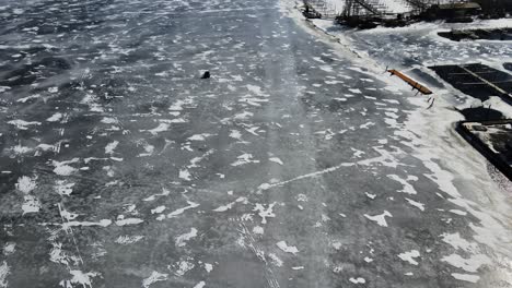 Inclinándose-Desde-La-Vista-De-Pájaro-Del-Hielo-Profundo-A-Mediados-De-Febrero-Hasta-La-Orilla-Del-Lago-Circundante-Del-Lago-Muskegon