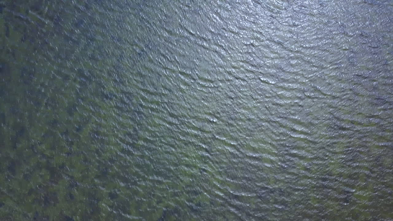 drone apuntado directamente hacia abajo mostrando movimiento abstracto, arrecife, olas, playa y orilla