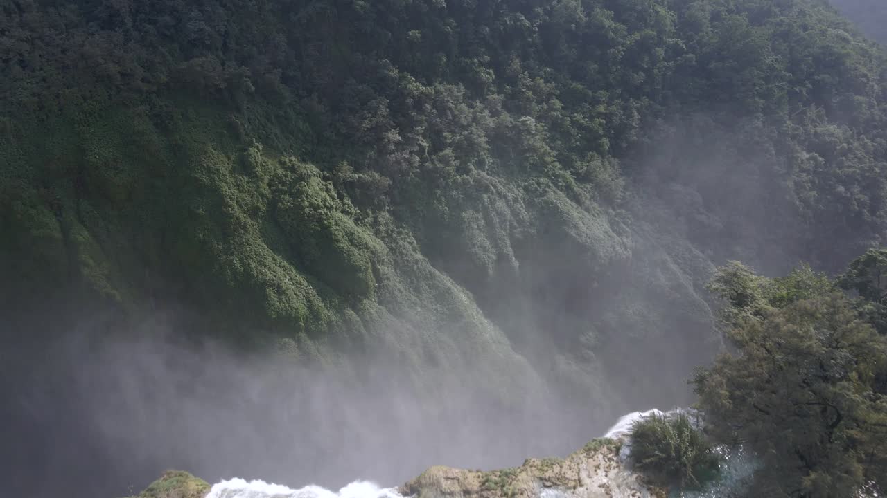 Drone dolly as mist flies into air from crashing water flowing from Tamul Waterfall, Mexico