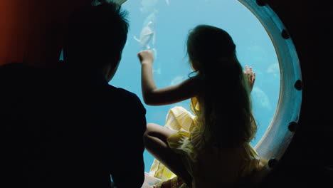 little girl with father at aquarium looking at fish swimming in tank little girl watching marine animals with curiosity dad teaching daughter about marine life in oceanarium