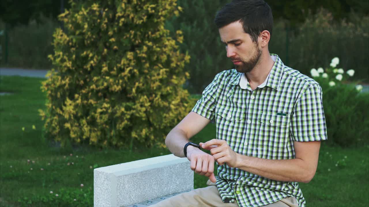 hombre comprobando el reloj inteligente en el parque