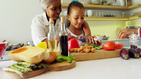 abuela ayudando a su nieta a cortar verduras en la cocina 4k