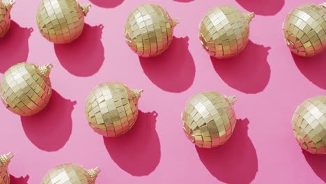 Video-of-rows-of-mirror-balls-and-their-shadows-on-pink-background