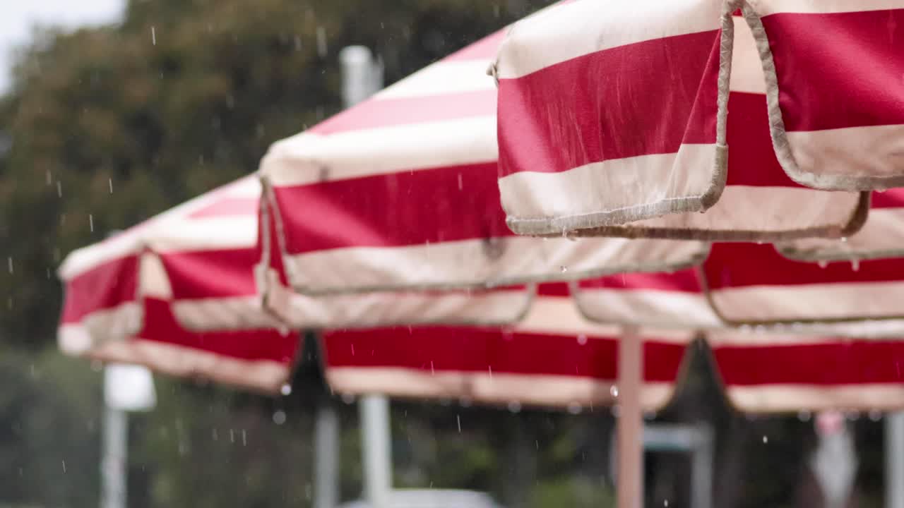 капли дождя падают на красные и белые тенты.