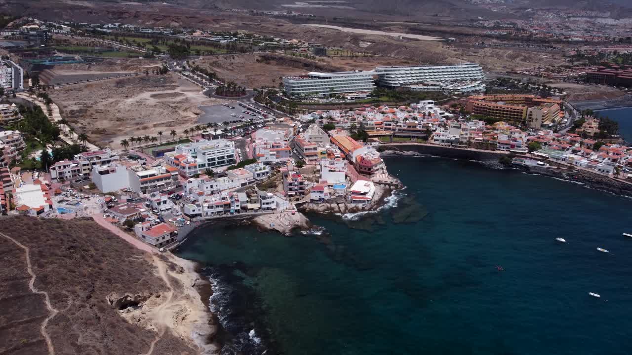 Drone view of small village by the ocean with mountains in the background in La Caleta, Tenerife, Canary Islands, Spain.