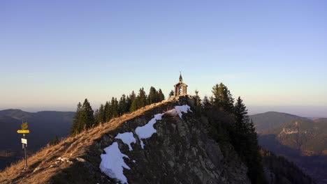 small wooden chapel on a ridge in the alps at golden hour