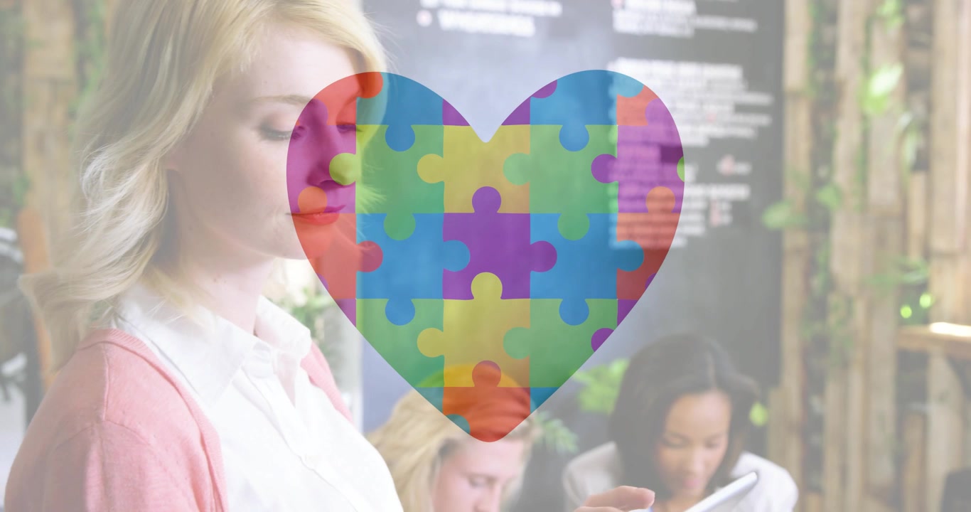 Pezzo di puzzle che appare formando un cuore in ufficio, donna bionda in cardigan che tocca il tablet per il team, spazio per il testo